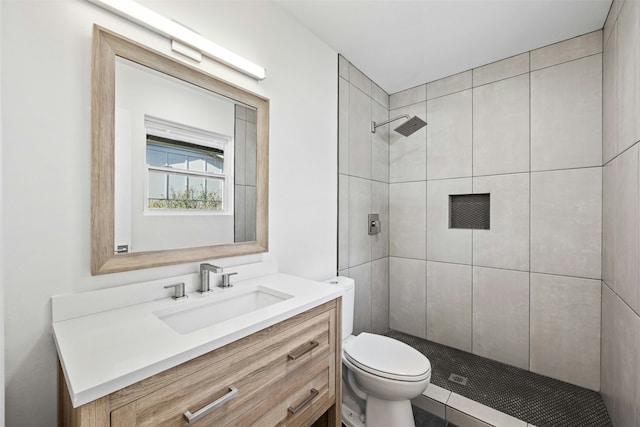 bathroom featuring toilet, vanity, and a tile shower