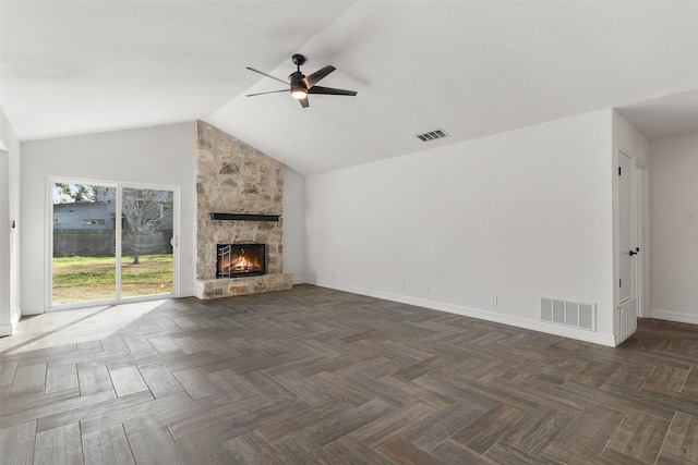 unfurnished living room featuring ceiling fan, a stone fireplace, dark parquet floors, and vaulted ceiling