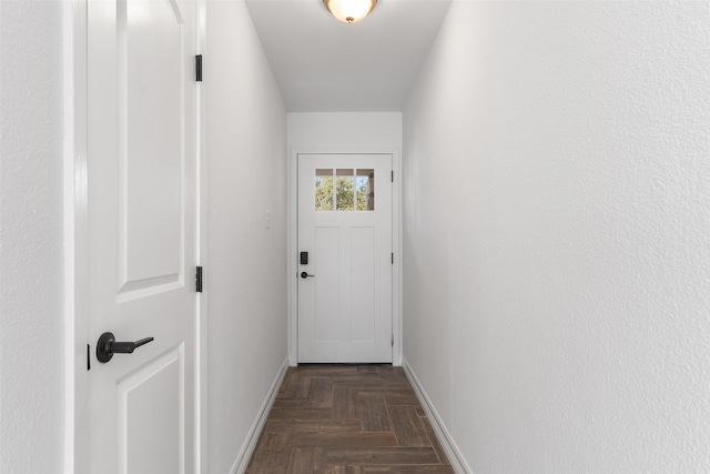 doorway to outside with dark parquet flooring