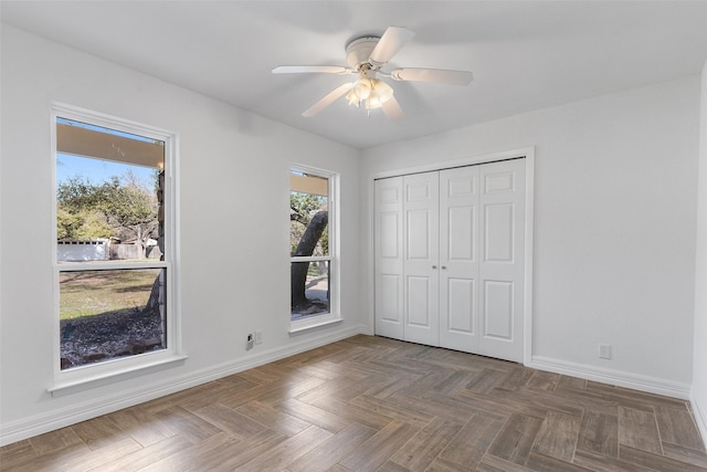 unfurnished bedroom with ceiling fan, a closet, and dark parquet flooring