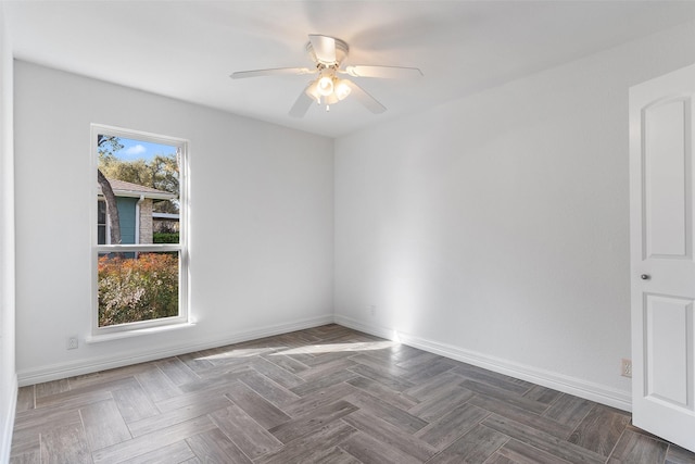 empty room with ceiling fan and dark parquet flooring