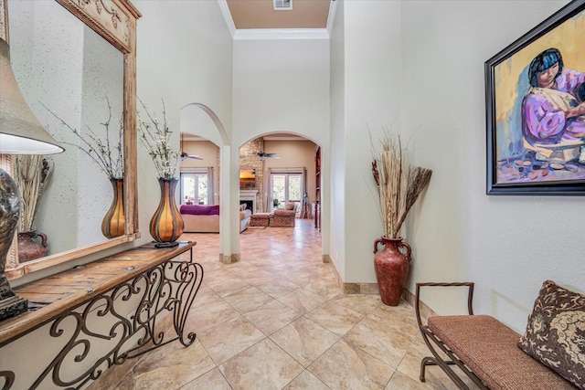 entryway featuring ceiling fan, a large fireplace, and ornamental molding