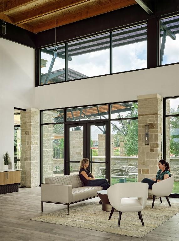 living room with plenty of natural light, wood finished floors, french doors, and a towering ceiling