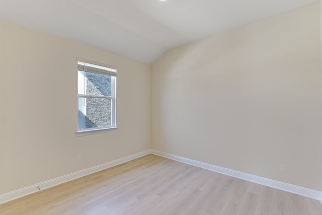 unfurnished room featuring vaulted ceiling, baseboards, and light wood-type flooring