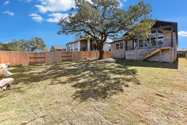 view of yard featuring stairs, central AC unit, and fence private yard