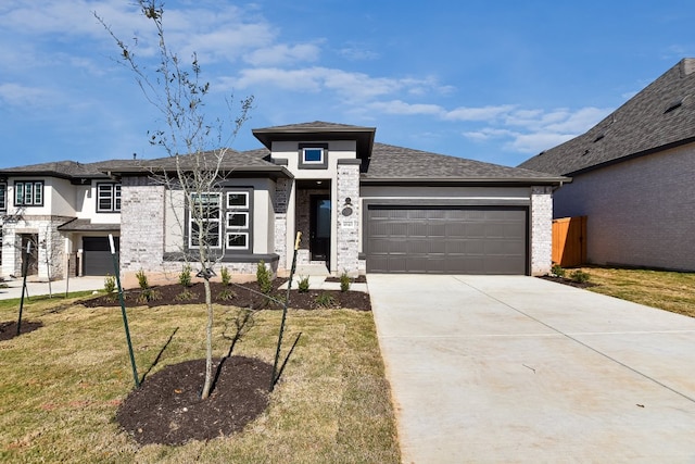 prairie-style home featuring concrete driveway, stone siding, a garage, and a front yard