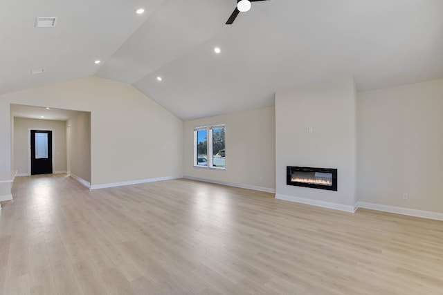 unfurnished living room with a glass covered fireplace, vaulted ceiling, a ceiling fan, and light wood-type flooring