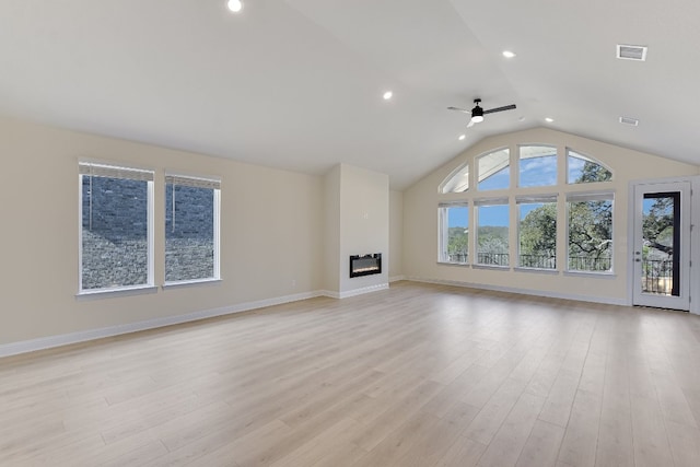 unfurnished living room with visible vents, light wood-style floors, a glass covered fireplace, and vaulted ceiling