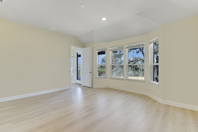 spare room with baseboards, lofted ceiling, and light wood finished floors