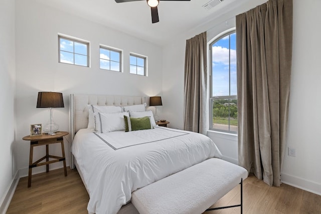 bedroom featuring ceiling fan, light hardwood / wood-style floors, and multiple windows