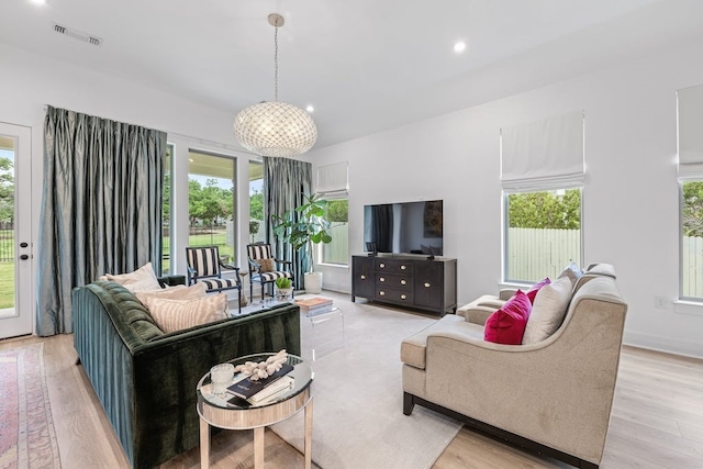 living room with plenty of natural light, light hardwood / wood-style flooring, and a chandelier