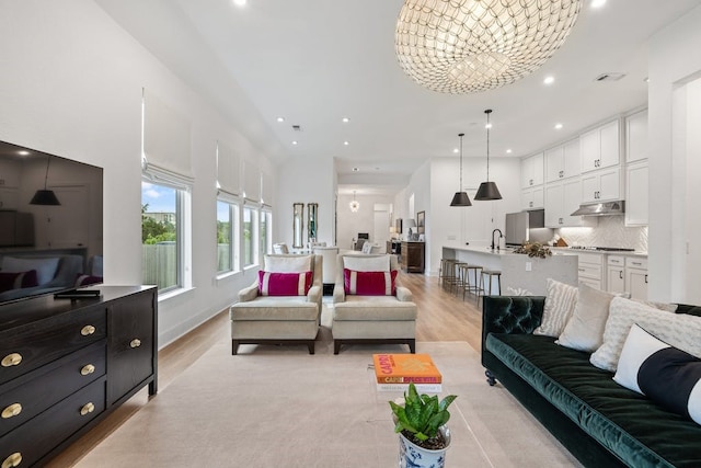 living room featuring sink, an inviting chandelier, and light hardwood / wood-style flooring