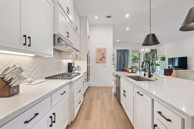 kitchen featuring decorative light fixtures, white cabinets, light stone countertops, and sink