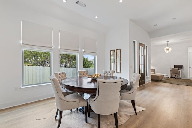 dining space with plenty of natural light, vaulted ceiling, an inviting chandelier, and light wood-type flooring