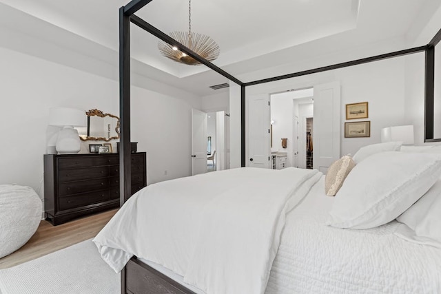 bedroom with ceiling fan, light wood-type flooring, and a raised ceiling