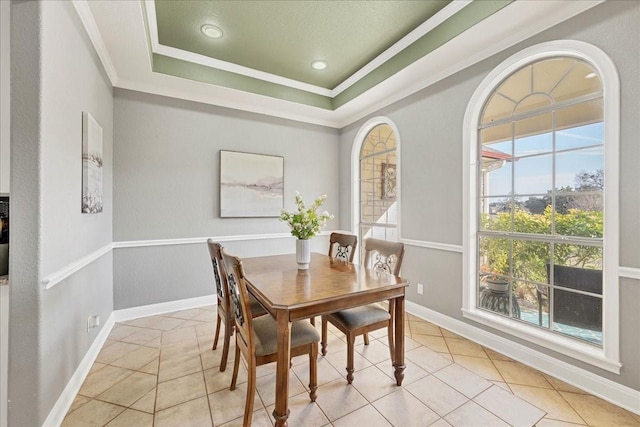 dining room featuring light tile patterned floors, a tray ceiling, and ornamental molding