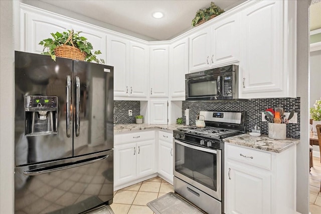 kitchen with backsplash, black appliances, white cabinetry, light stone countertops, and light tile patterned floors