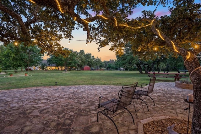 patio terrace at dusk featuring a yard