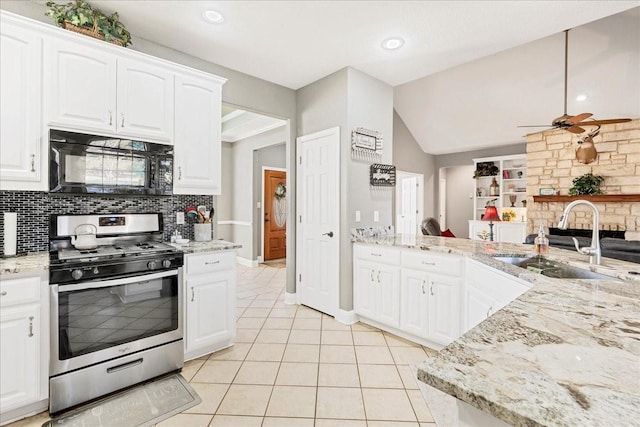 kitchen featuring backsplash, sink, light tile patterned floors, white cabinets, and gas range