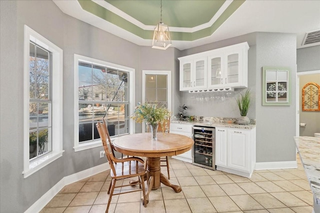 bar with white cabinetry, beverage cooler, a raised ceiling, and light stone countertops