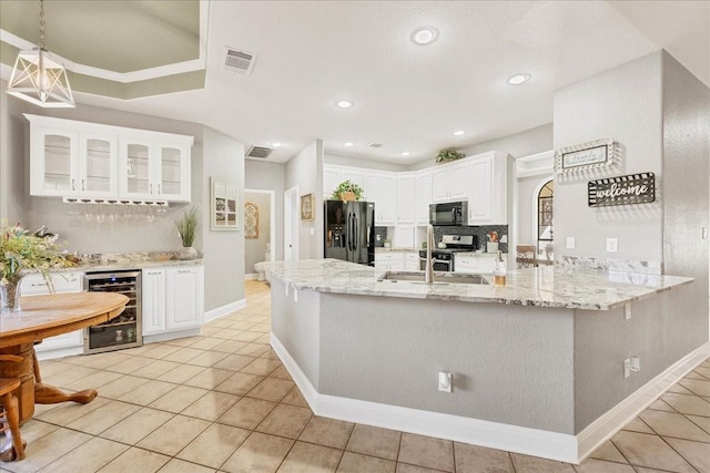 kitchen with kitchen peninsula, beverage cooler, black appliances, white cabinets, and sink