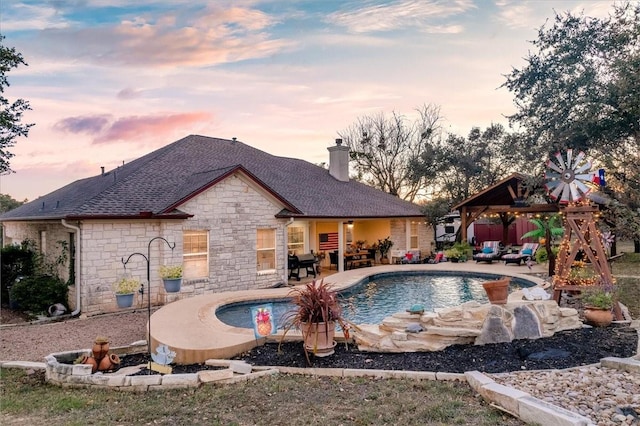 pool at dusk featuring a gazebo and a patio area