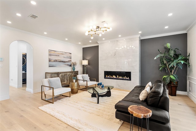 living room with light wood-type flooring, ornamental molding, and a fireplace