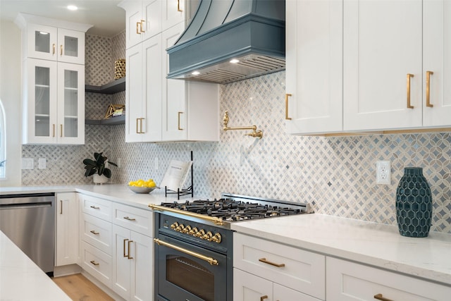 kitchen featuring dishwasher, gas stove, white cabinetry, backsplash, and custom range hood