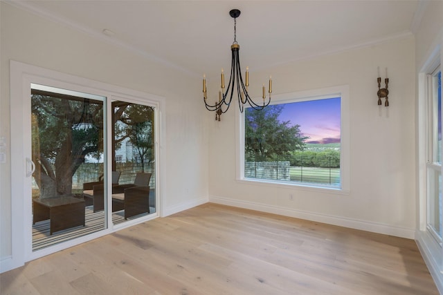 unfurnished dining area featuring an inviting chandelier, ornamental molding, and light hardwood / wood-style floors