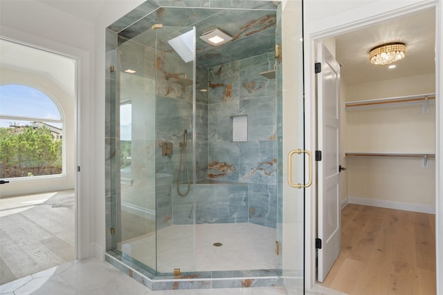 bathroom with a shower with shower door, a chandelier, and hardwood / wood-style flooring