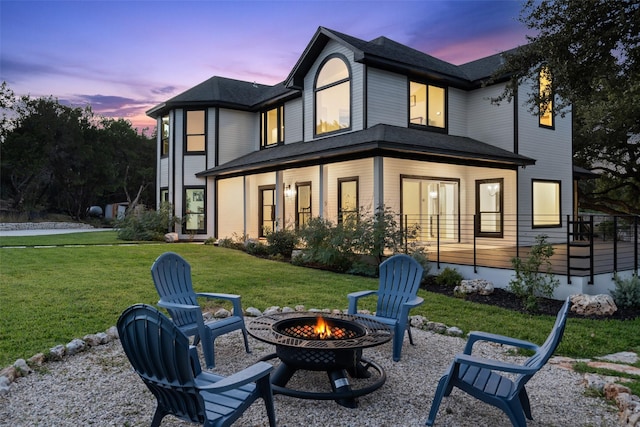 back house at dusk featuring an outdoor fire pit and a yard