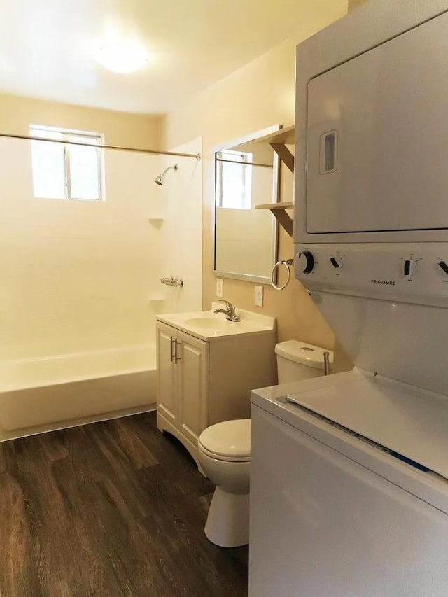 full bathroom featuring toilet, vanity, wood-type flooring,  shower combination, and stacked washer and dryer