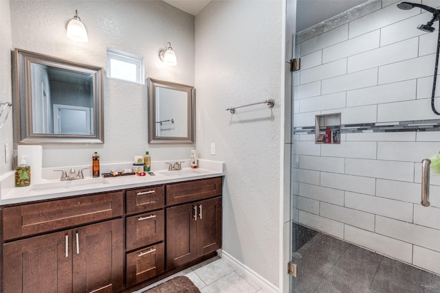 bathroom featuring tile patterned flooring, tiled shower, and vanity