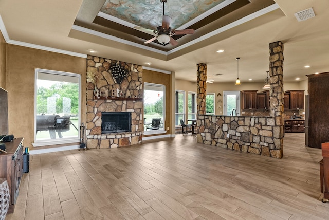 living room featuring ceiling fan, plenty of natural light, crown molding, and a fireplace