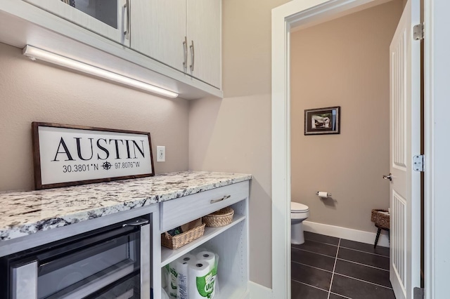 interior space featuring toilet, wine cooler, and tile patterned flooring