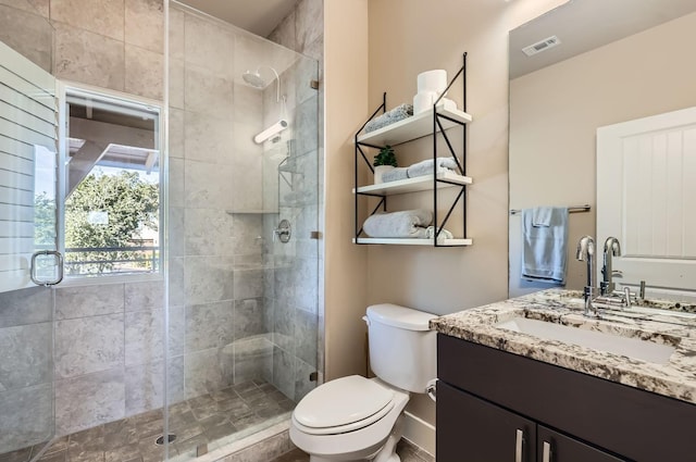 bathroom featuring toilet, vanity, and a shower with door