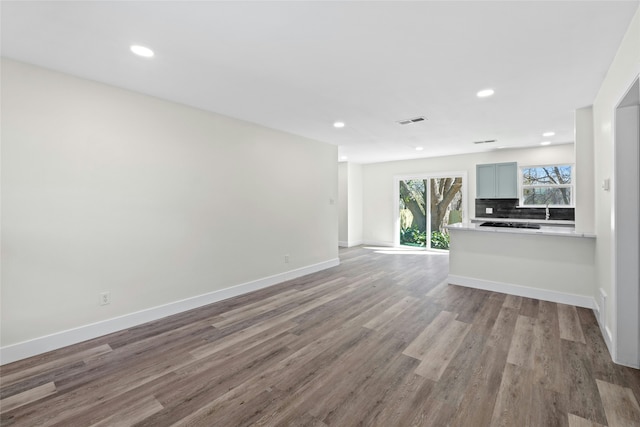 unfurnished living room with sink and hardwood / wood-style floors