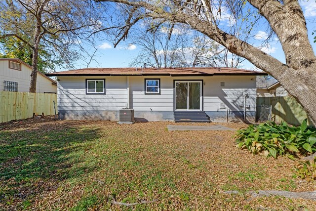 rear view of house featuring central AC unit and a yard