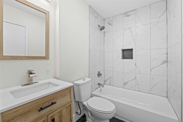 full bathroom featuring tiled shower / bath combo, vanity, and toilet