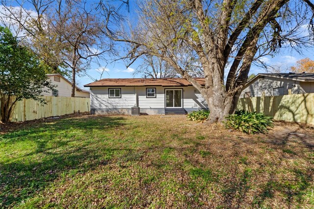 rear view of property with a lawn and central air condition unit