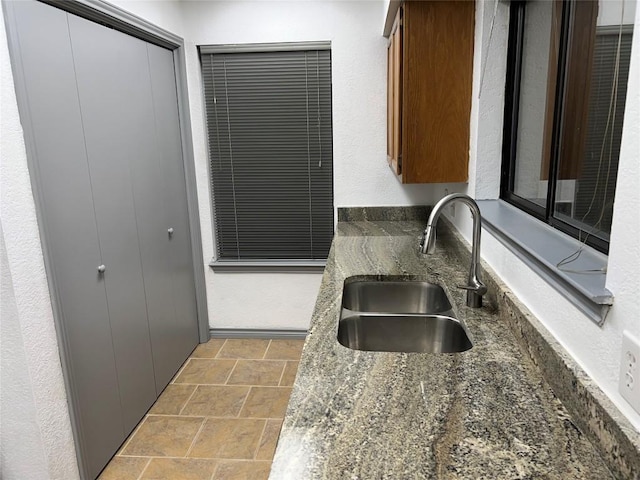 8200 Neely Dr Unit 117, Austin, TX 78759 - kitchen with a sink, stone finish floors, dark stone countertops, and brown cabinetry