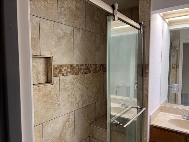 bathroom featuring a shower with shower door and vanity