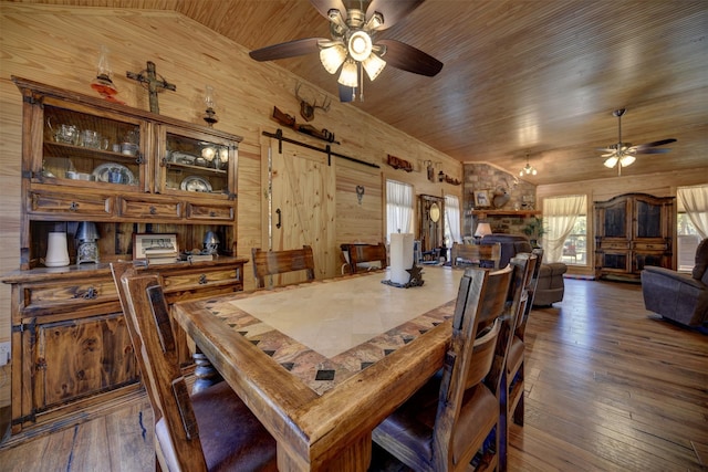 dining area featuring wood ceiling, wooden walls, a barn door, and dark hardwood / wood-style flooring