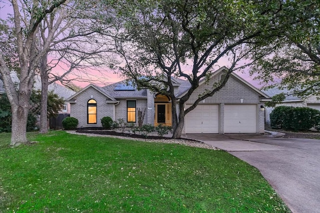 6817 Beatty Dr, Austin, TX 78749 - view of front of home with brick siding, an attached garage, concrete driveway, and a yard