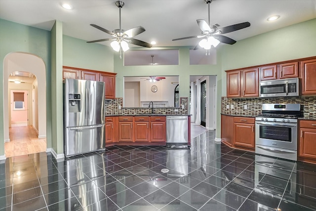 kitchen with decorative backsplash, sink, a high ceiling, and stainless steel appliances