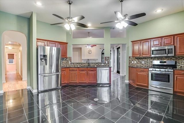 6817 Beatty Dr, Austin, TX 78749 - kitchen with appliances with stainless steel finishes, a ceiling fan, dark countertops, arched walkways, and recessed lighting