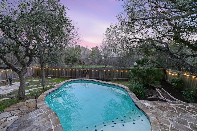 pool at dusk with a patio area