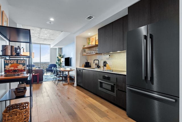 kitchen featuring stainless steel appliances, decorative backsplash, sink, light wood-type flooring, and floor to ceiling windows