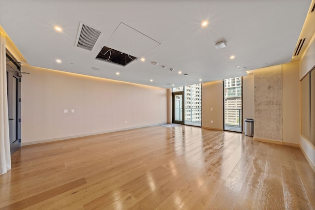 unfurnished room featuring a wall of windows and light hardwood / wood-style flooring