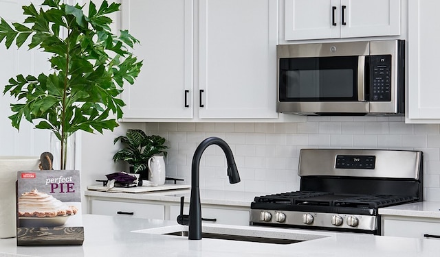 kitchen featuring white cabinetry, sink, backsplash, and appliances with stainless steel finishes